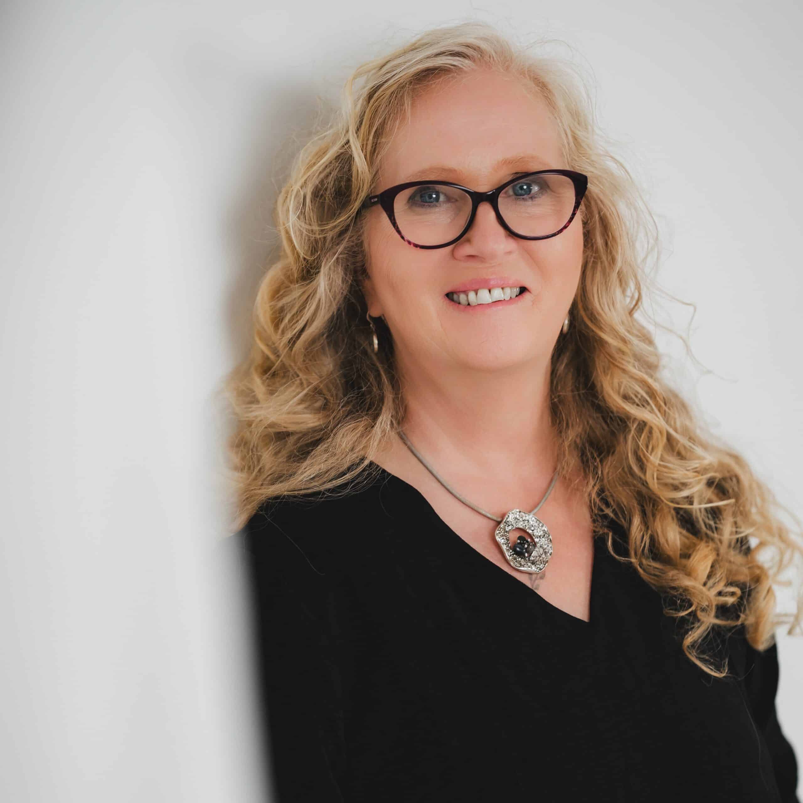 Lächelnde Frau mit lockigem Haar und Brille