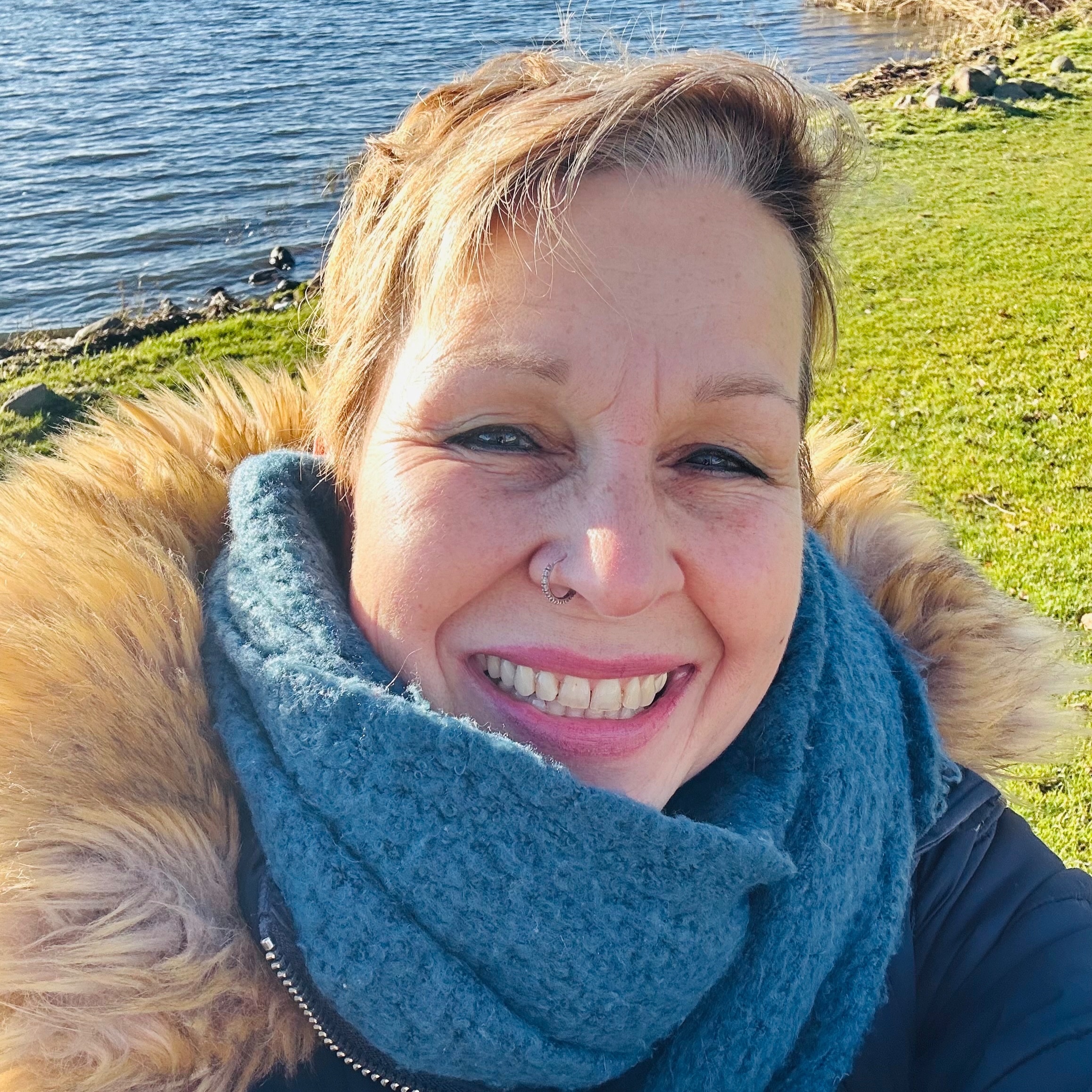 Lächelnde Person am Seeufer bei Sonne