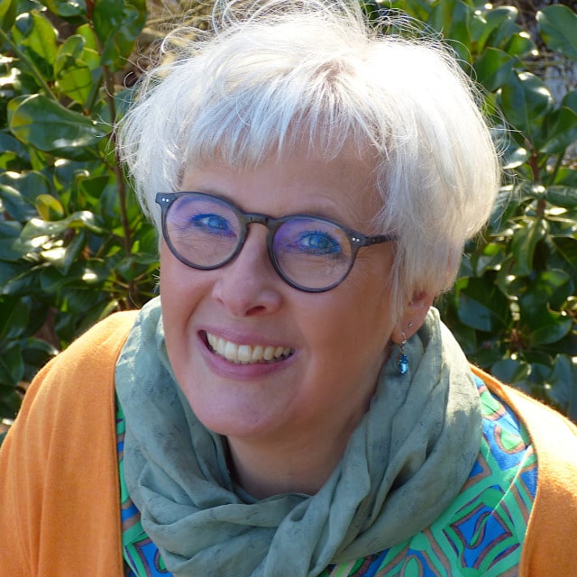 Lächelnde Frau mit Brille im grünen Schal draußen